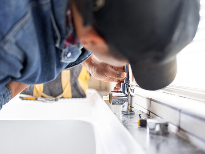 Plumber fixing faucet, plumbing and maintenance with man, manual labour and home renovation with trade. Construction, handyman with kitchen or bathroom sink with hardware, pipe and DIY with vocation