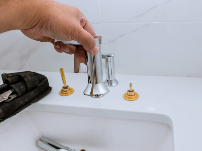 Plumber installing new mixer tap hands worker close up repair in bathroom at home plumbing repair service