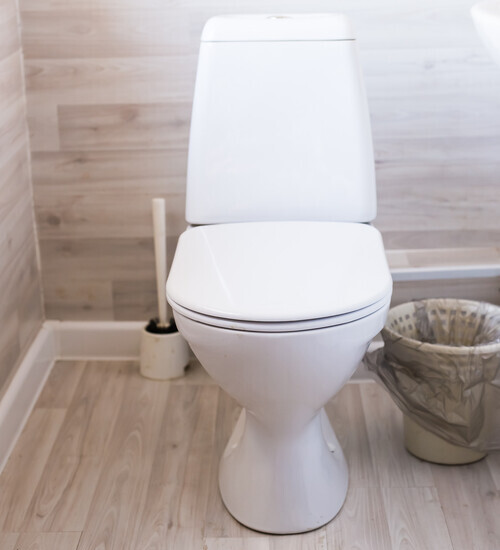 New ceramic toilet bowl near light wall